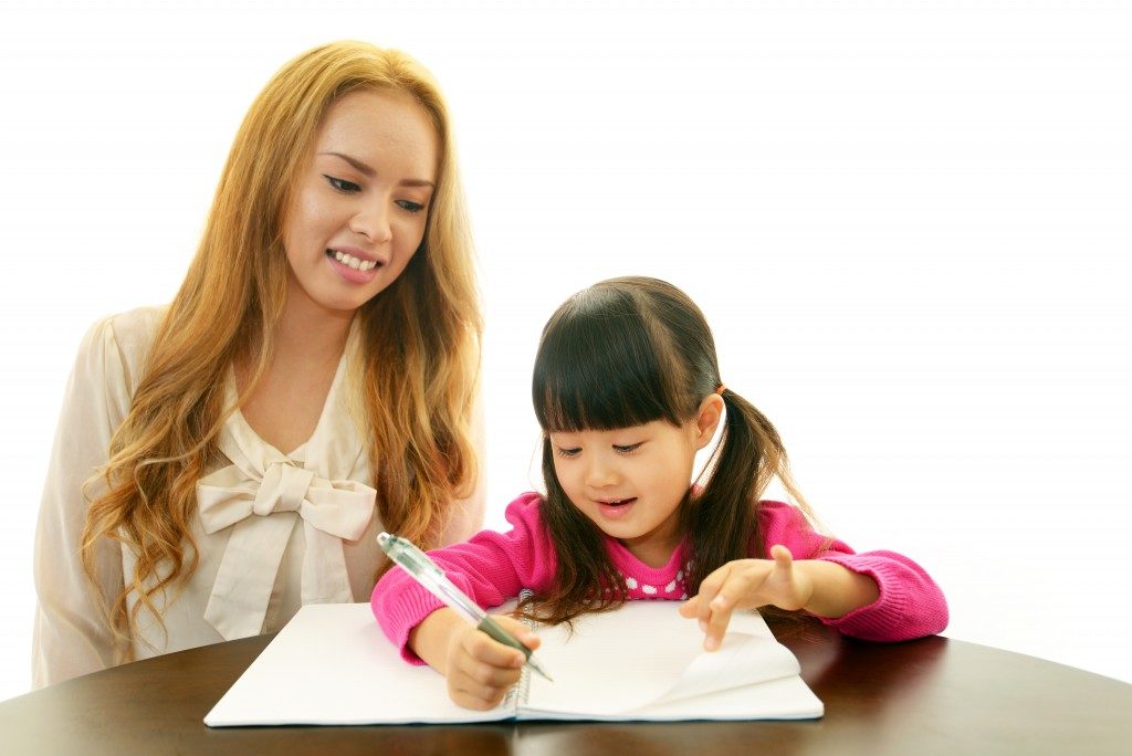 Little girl studying with teacher