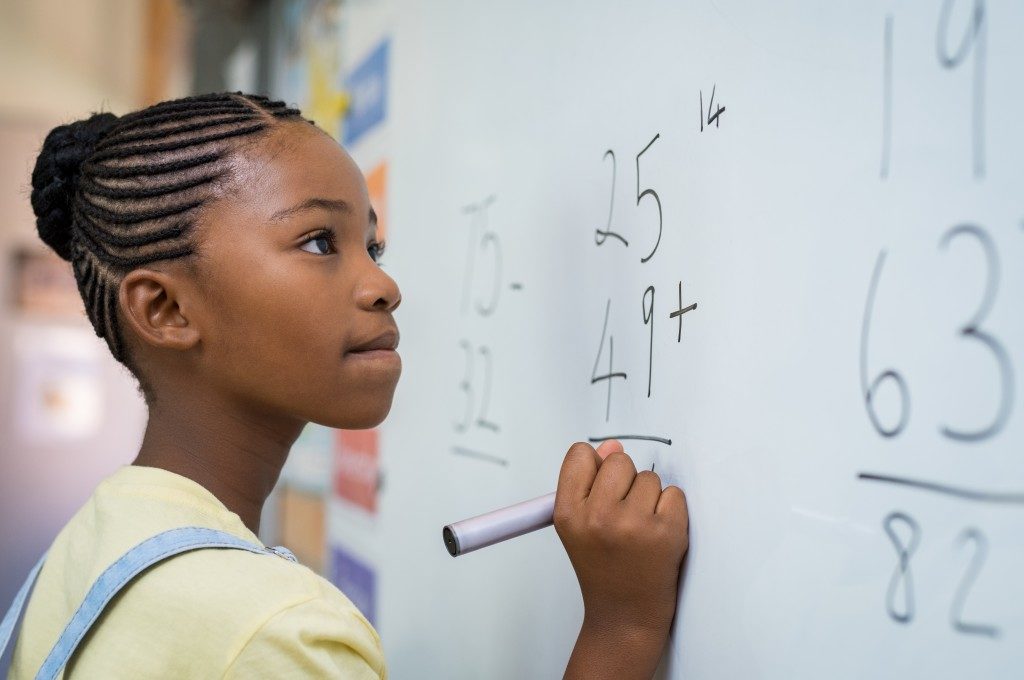 girl solving math problem on the board