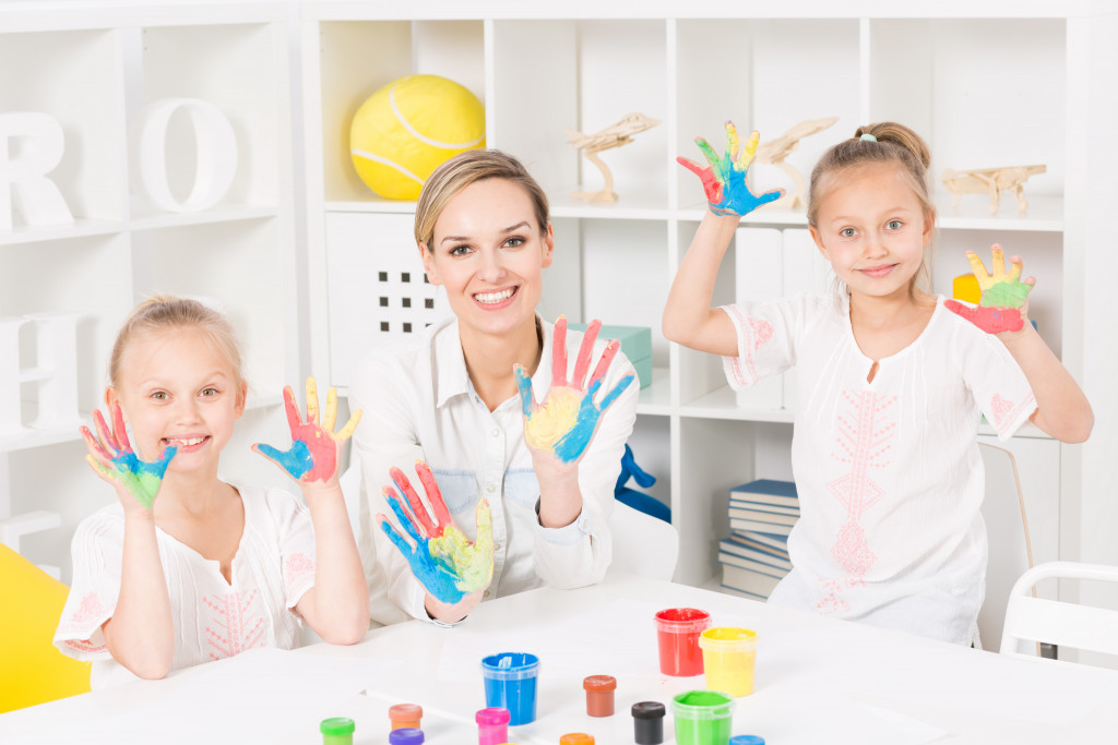cheerful kids doing painting with teacher